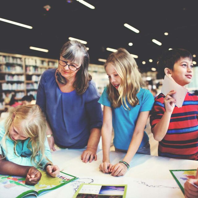 Teacher and group of students reading a map in a library