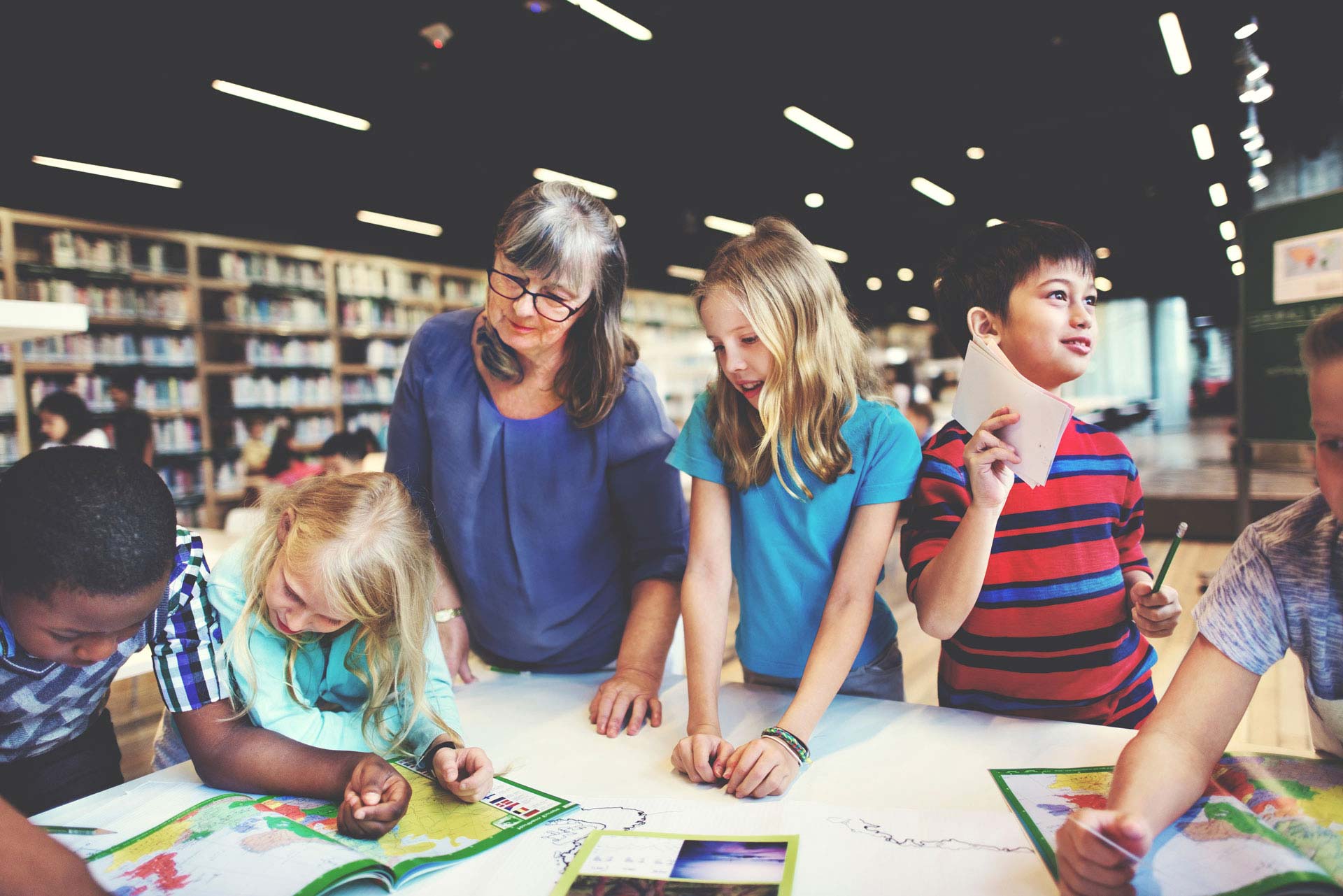 Teacher and group of students reading a map in a library