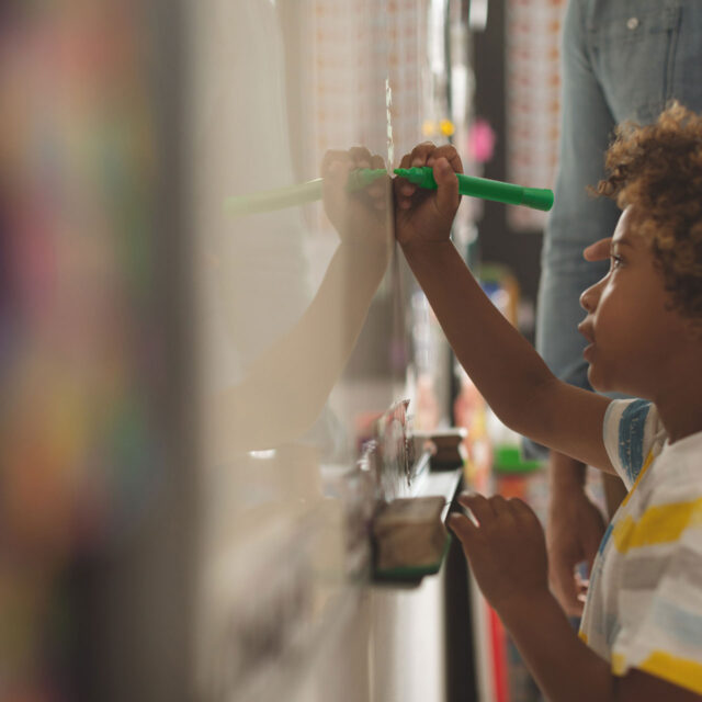 Elementary school student with a green highlighter on a whiteboard