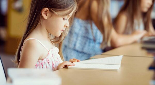 An elementary student reads a book in class.