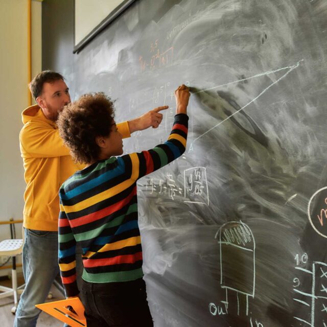 male math student at chalkboard with teacher