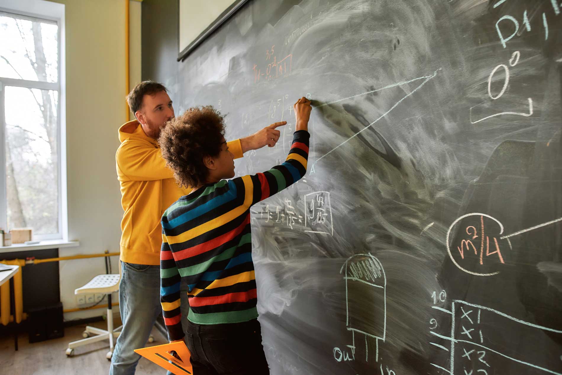 male math student at chalkboard with teacher