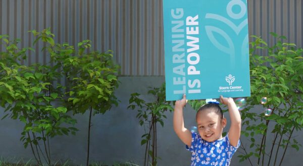 A student holds a poster above her head that says, “LEARNING IS POWER.”