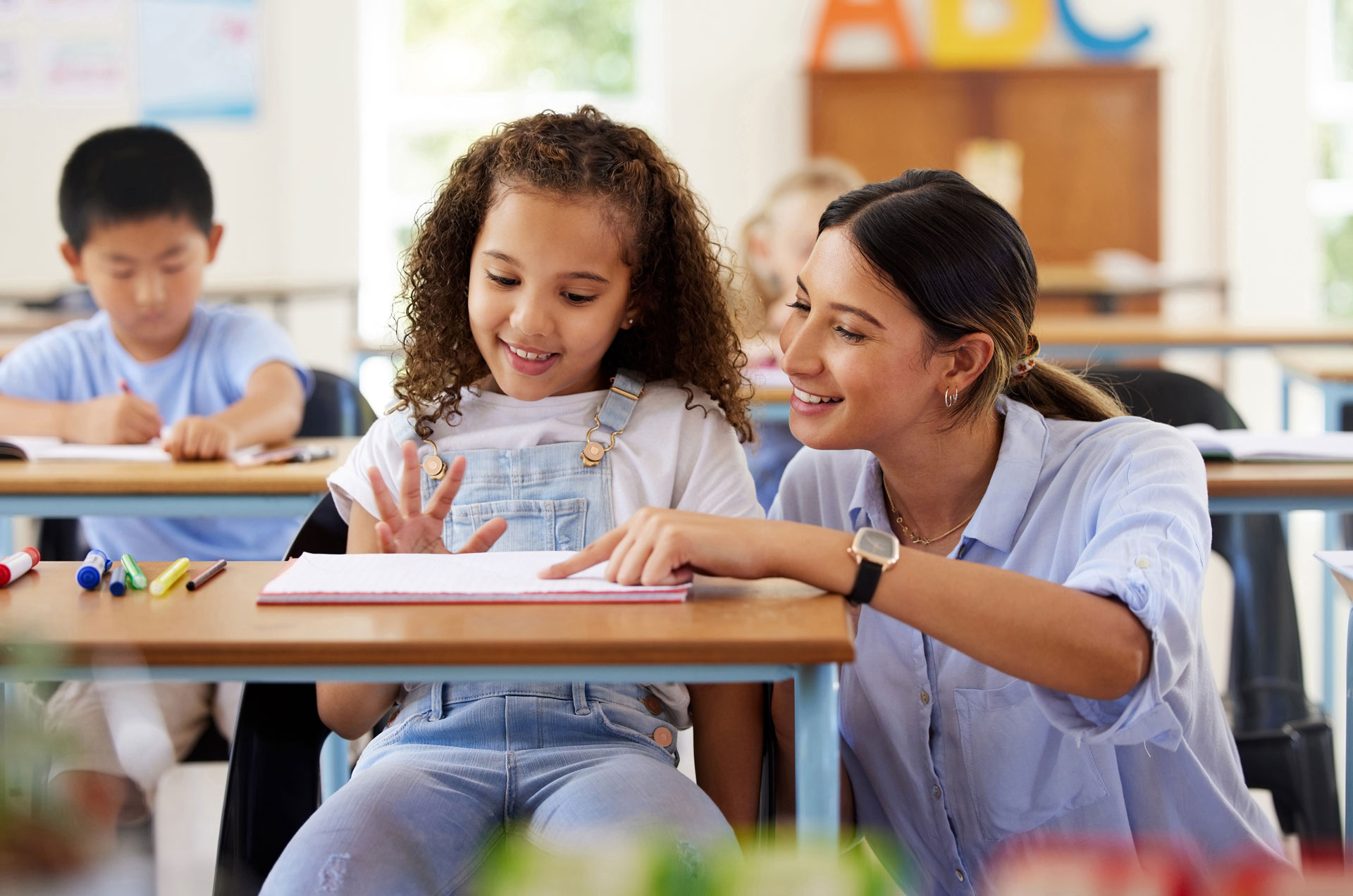 Teacher helps a student in an elementary classroom.