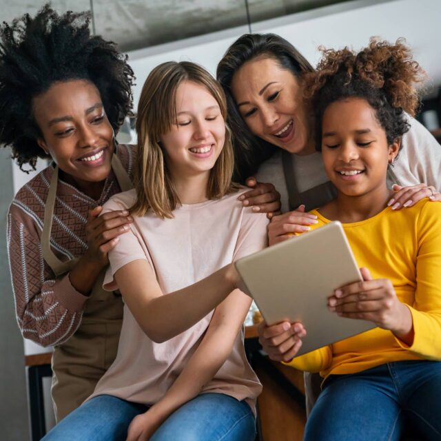 Two happy mothers and daughters reviewing a financial assistance form