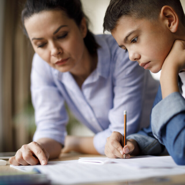 A mother helps her son with homework
