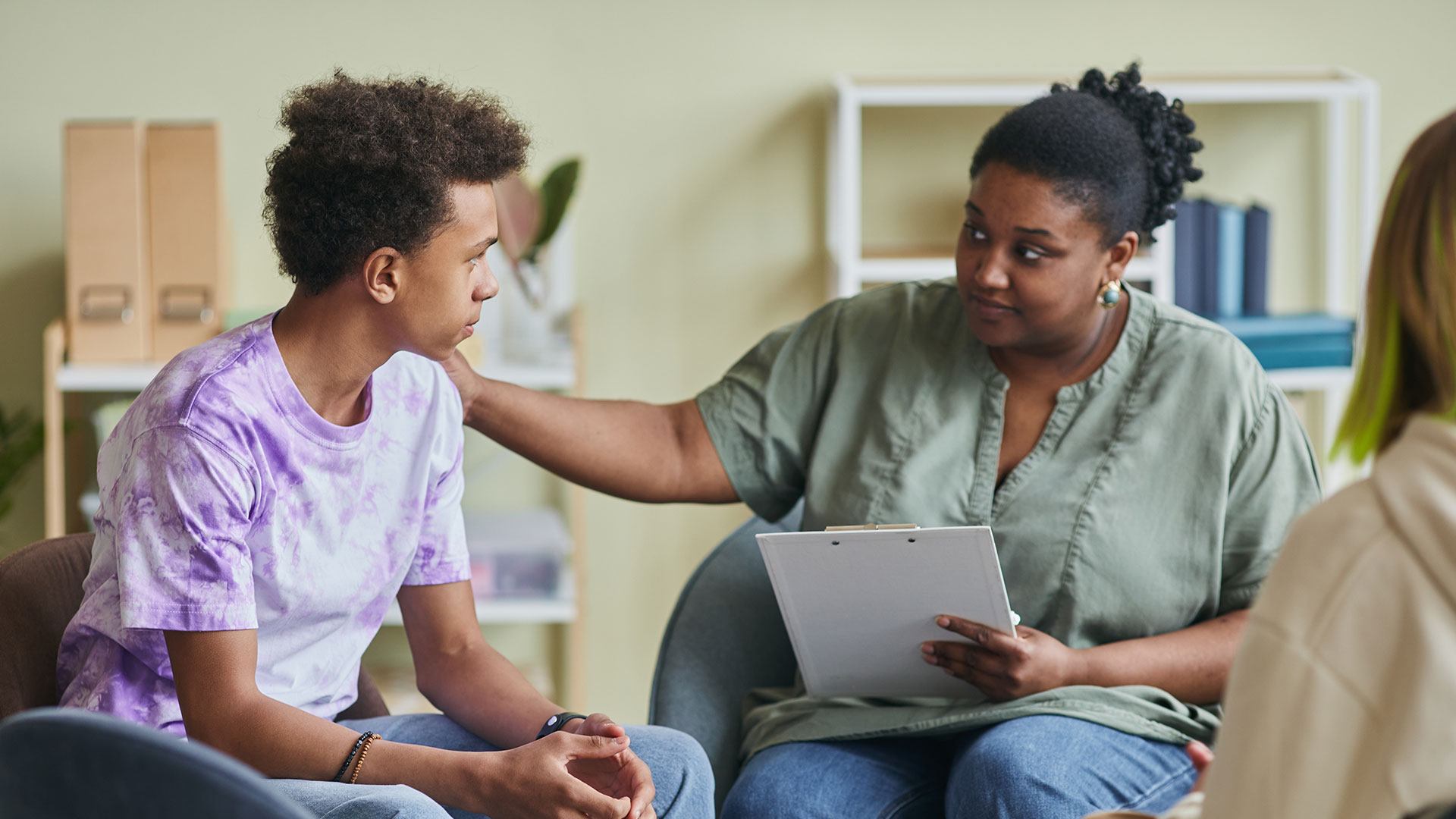 A therapist supports a high school student in a group session.