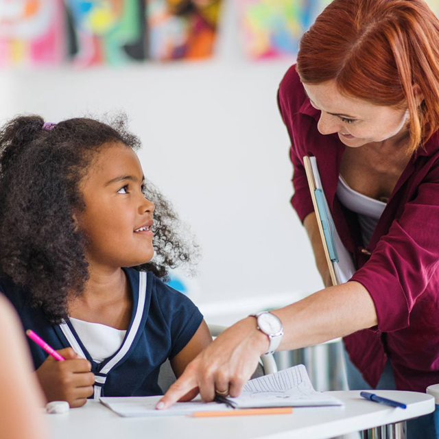 Teacher instructing student in a classroom.